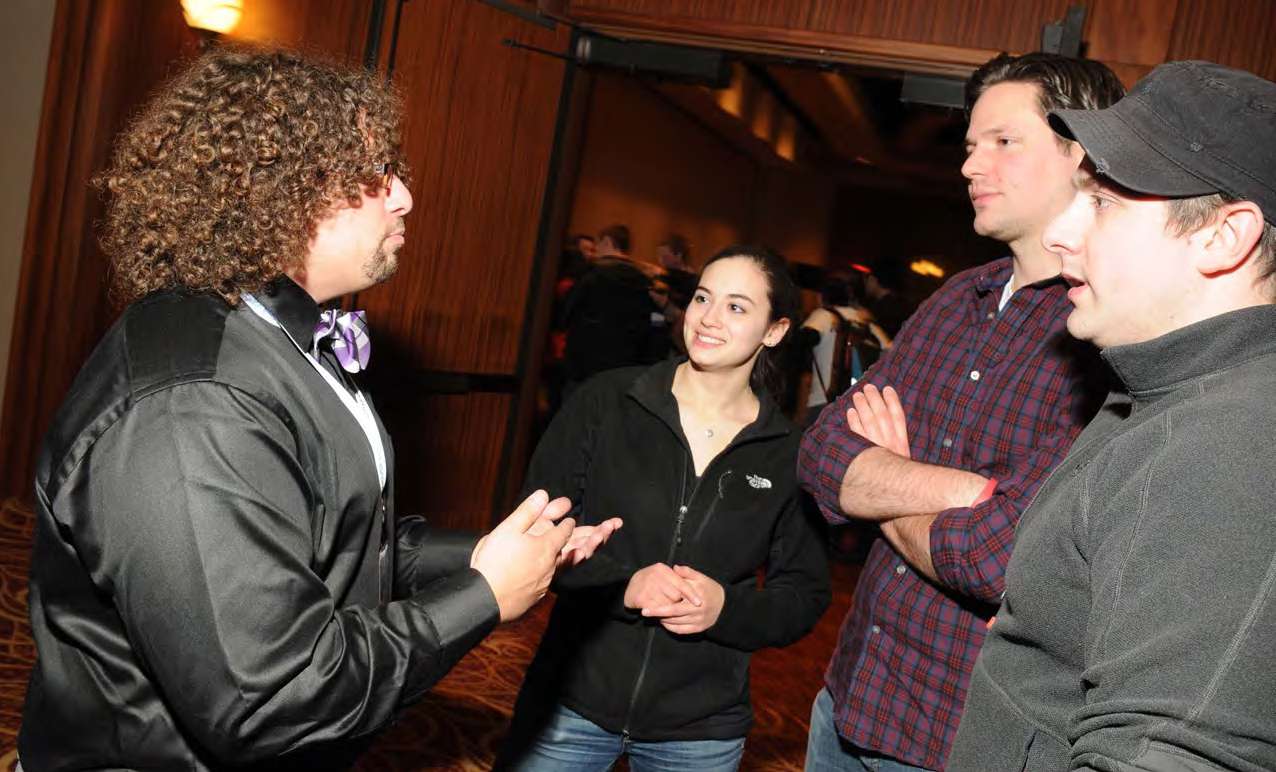 Four people engaged in conversation in a hotel conference facility hallway.